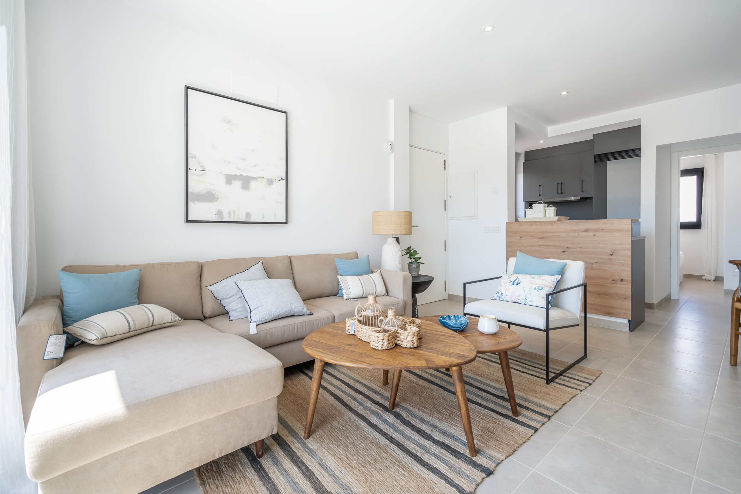 Helles, modern eingerichtetes Wohnzimmer mit offener Küche, Essbereich und gemütlicher Sitzecke, kombiniert mit natürlichen Holzelementen und neutralen Farbtönen.